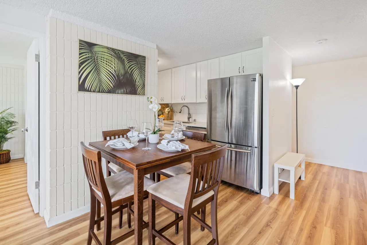 Dining table set for a meal beside the full kitchen and stainless refrigerator