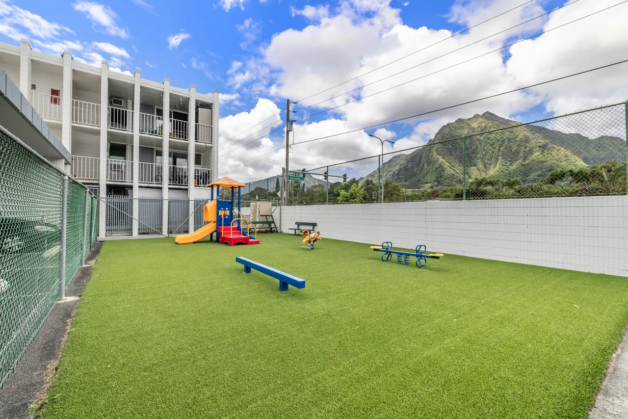 Grassy common area and children's playground beneath the mountains