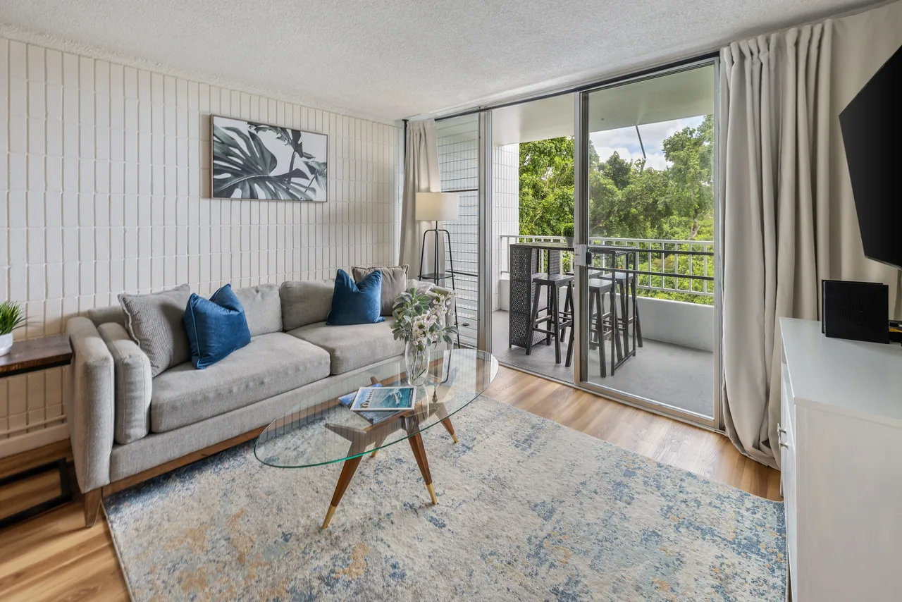 Open living area with sofa and lanai access, finished in warm honey-oak flooring